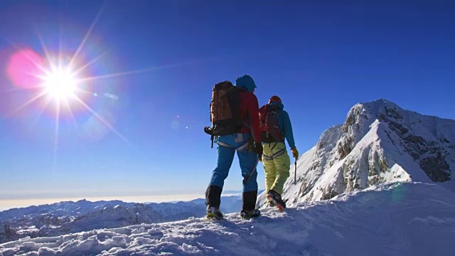 登山运动员在阳光下爬上白雪覆盖的山脊视频素材