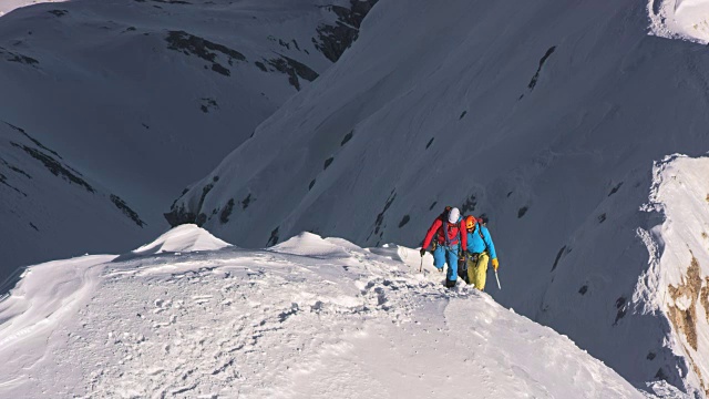 登山运动员爬上被雪覆盖的陡峭山脊视频素材