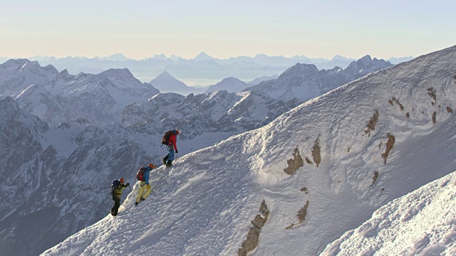 阳光下，登山队员们登上了雪山的山脊视频素材