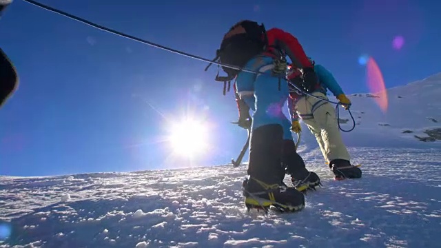 绳索登山队在阳光下行走在雪山上视频素材