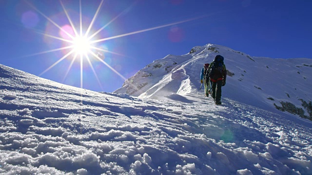 在一个阳光明媚的日子里，带着冰爪走在雪山上视频素材