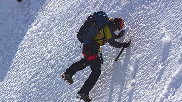 登山者正用冰斧攀登白雪覆盖的斜坡视频素材