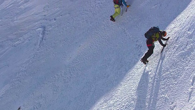 图为登山运动员正在爬过白雪覆盖的陡坡视频素材