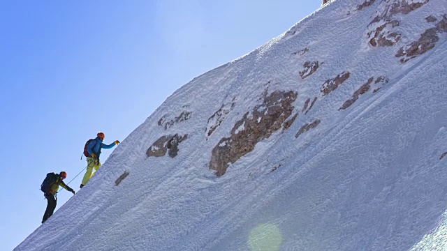 两个登山者正在爬上陡峭的雪坡视频素材