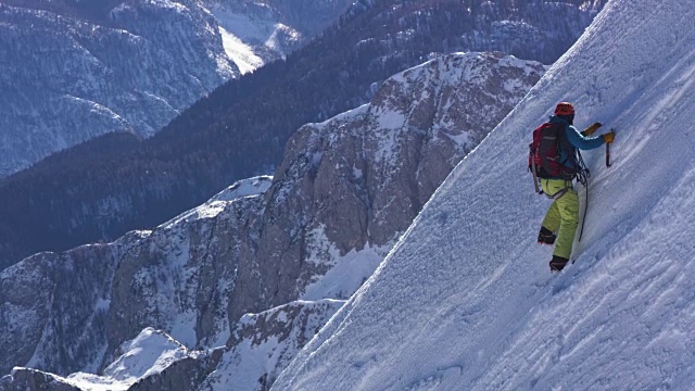 一位登山运动员正在攀登白雪覆盖的山峰视频素材