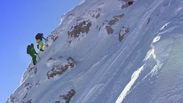 登山运动员在冬天攀登积雪的陡坡视频素材