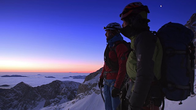 黄昏时分，一群登山队员站在雪山顶上视频素材