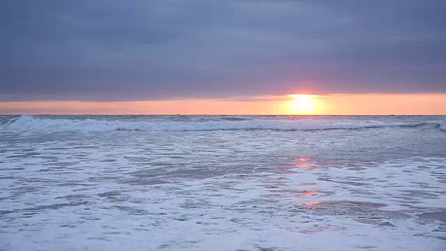 当太阳落山时，海浪撞击着海滩视频素材