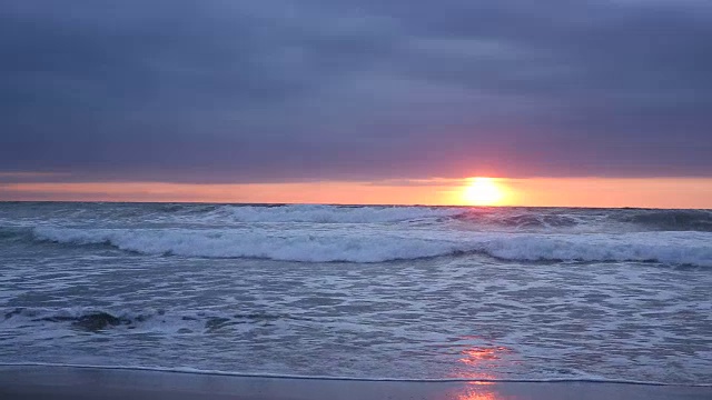 当太阳落山时，海浪撞击着海滩视频素材