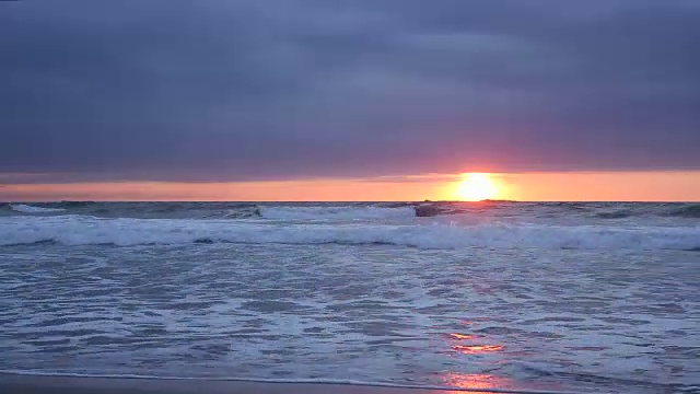 当太阳落山时，海浪撞击着海滩视频素材