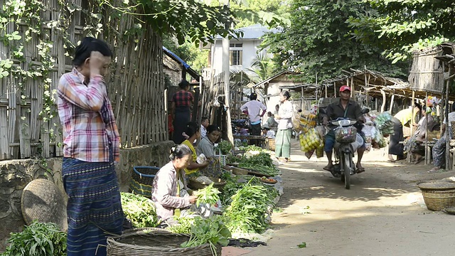 缅甸曼德勒省蒲甘市，一名妇女在卖蔬菜，一辆摩托车载着货物行驶在myinkaba市场视频素材