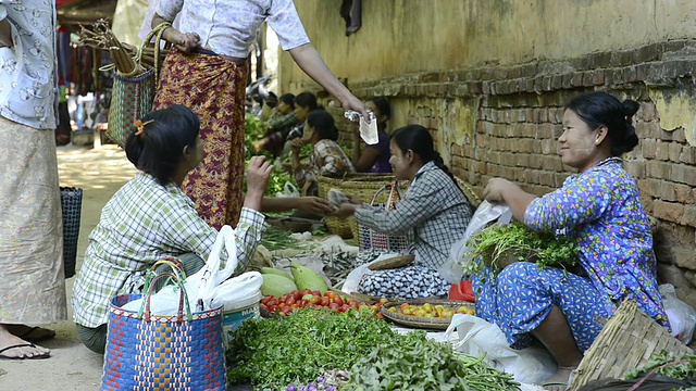 缅甸曼德勒省蒲甘市，女人们在女市场上卖菜，买家付钱视频素材