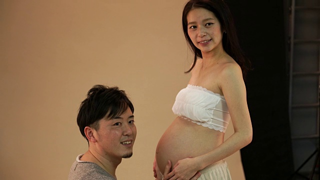 一对新婚夫妇正在摄影棚里拍一张孕妇照视频素材