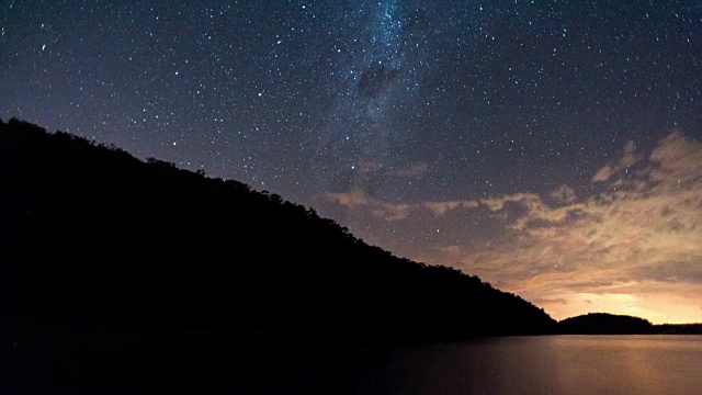 在夜晚，线性的和泛型的时间流逝，一座山的剪影和一个水坝与银河系和戏剧性的雷暴视频素材