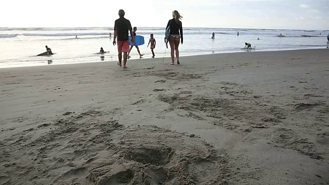 父亲和女儿抓住冲浪板，朝着海浪走去视频素材