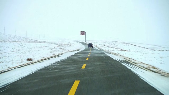 汽车在下雪的天气行驶在道路上，新疆，中国。视频素材