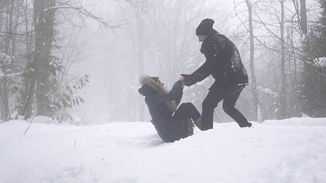 慢镜头女子将男子拉入雪中视频素材