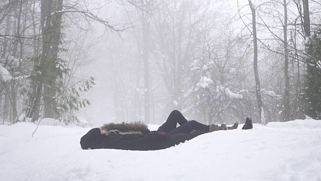 慢镜头女子将男子拉下雪地视频素材