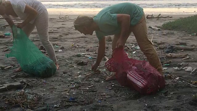 成熟的夫妇在广阔的海滩上收集垃圾，日出视频素材