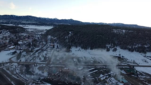 高空鸟瞰帕戈萨斯普林斯科罗拉多温泉蒸汽提升冬季积雪覆盖的落基山脉视频素材