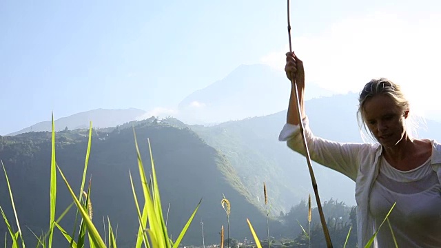 女人走在山路上，后面是火山视频素材