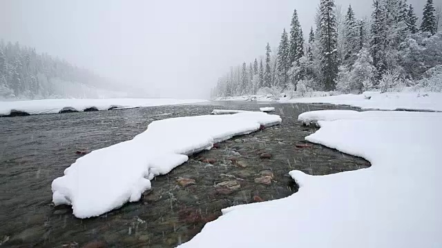 广角拍摄的河流在山上与积雪覆盖的树木和河岸覆盖在大雪暴风雪。视频素材