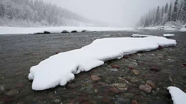 广角拍摄的河流在山上与积雪覆盖的树木和河岸覆盖在大雪暴风雪。视频素材