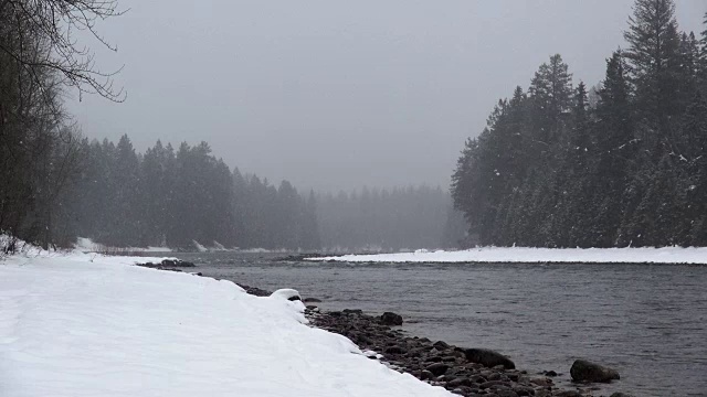 长焦拍摄的雪覆盖的河流与大雪从天空落在山上。视频素材