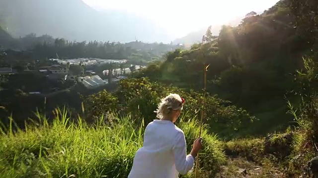 女人走在山路上，后面是火山视频素材