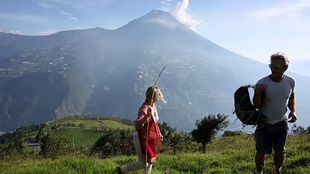 情侣们穿过火山下的高山草地，然后放松视频素材