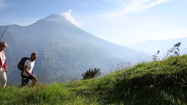 情侣们穿过火山下的高山草地，然后放松视频素材