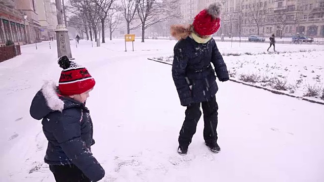 女孩(13)和小男孩(3)抖掉雪。视频素材