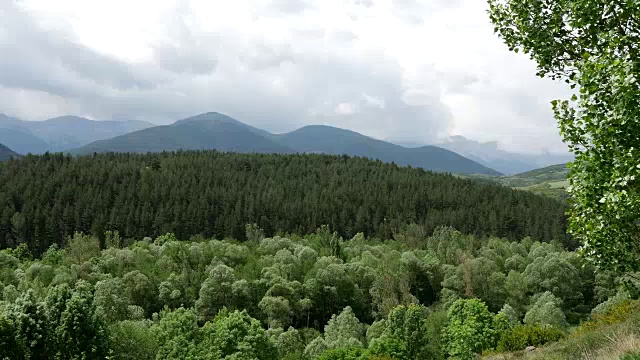 西班牙比利牛斯山的云朵覆盖着树木繁茂的山丘和山脉视频素材