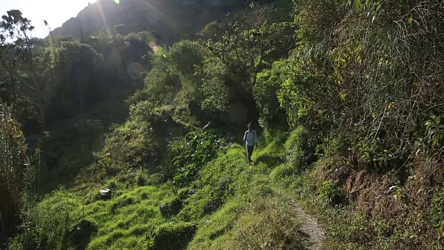 一个人戴着帽子沿着山路走视频素材