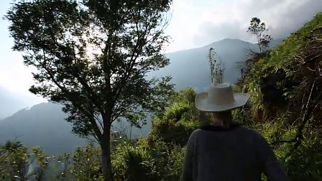 一个女人戴着帽子沿着山路走视频素材