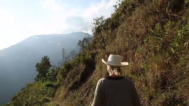 一个女人戴着帽子沿着山路走视频素材