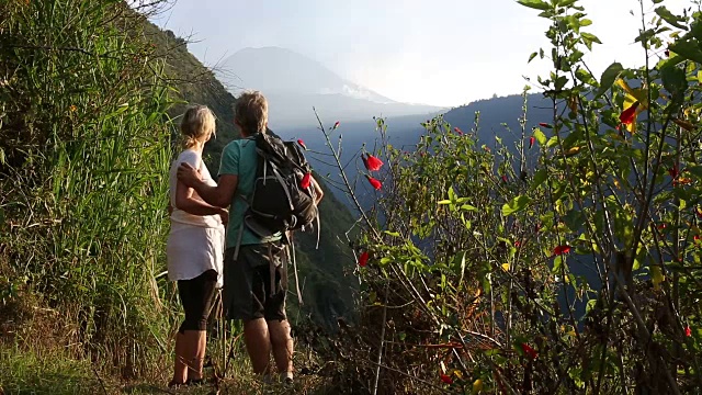 徒步情侣走到山边的小路，上面是火山视频素材