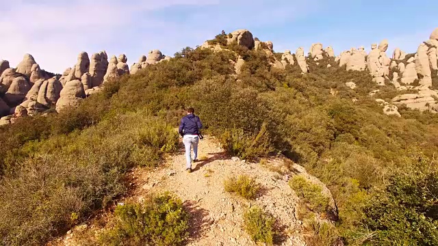 一名徒步旅行者在蒙特塞拉特山行走，在地球上一个独特的地方，以所有的峭壁山峰为背景。视频素材