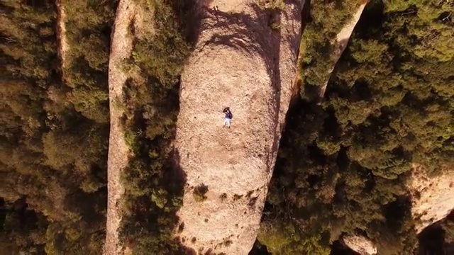 在蒙特塞拉特山脉，一名徒步旅行者躺在岩石上用无人机拍摄空中自拍。视频素材