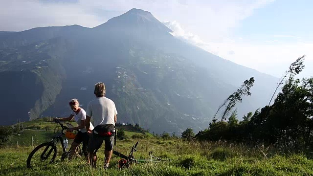 夫妇放松与自行车在山草地，火山后面视频素材