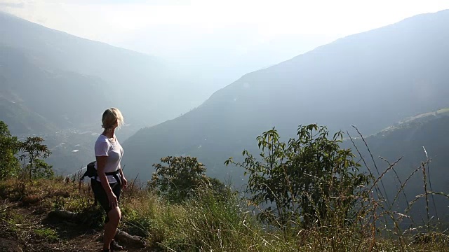 女人爬上山间小路，越过山谷视频素材