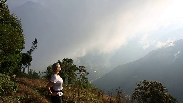 女人爬上山间小路，在薄雾中越过山谷视频素材