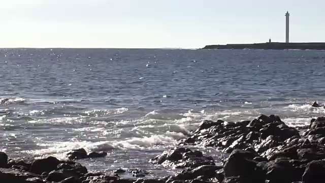 海浪在岩石海岸与地平线、岬角和灯塔视频素材