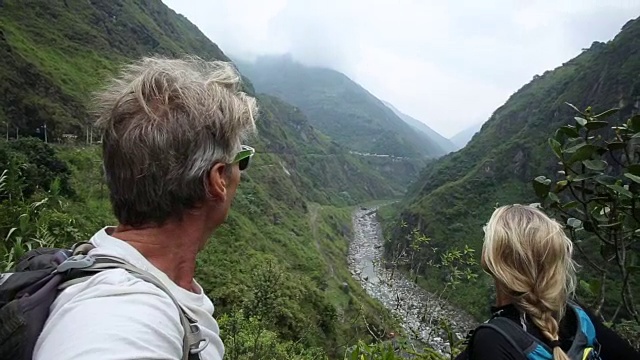 徒步旅行的夫妇在绿色河谷上停下来，向前看视频素材