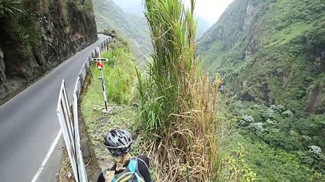 女自行车手停在绿色山谷上方的山路边视频素材