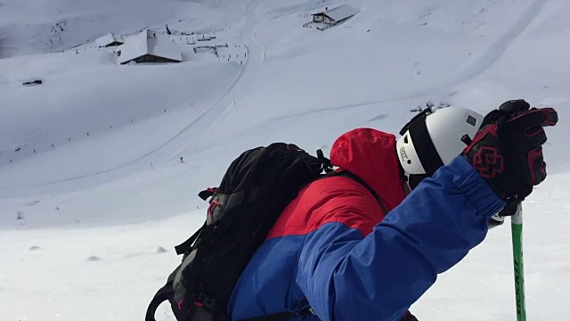 一个野外滑雪者的慢动作镜头准备滑下山坡，穿过厚厚的积雪。粉。视频下载