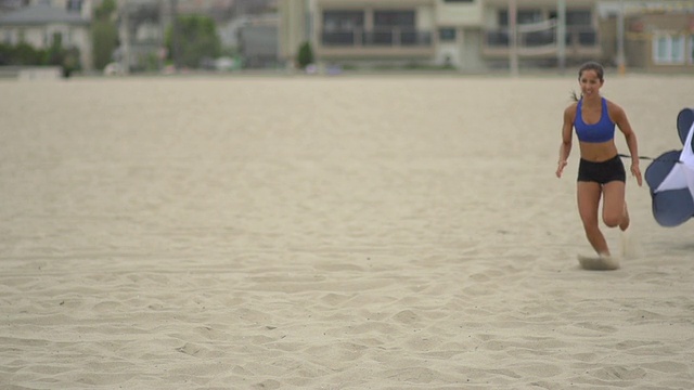 一个年轻女子在海滩上用降落伞做速度和敏捷性训练。-超级慢动作-拍摄240帧/秒视频素材