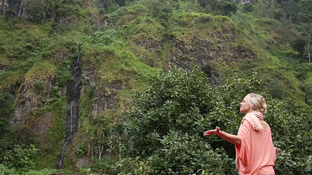 女人走下热带雨林悬崖，瀑布视频素材