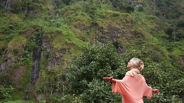 女人走下热带雨林悬崖，瀑布视频素材