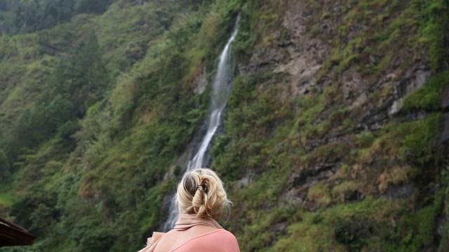 女人走下热带雨林悬崖，瀑布视频素材